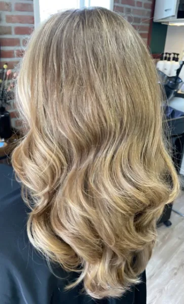 Deze dame met donker blond lang blond haar heeft prachtige highlights en lowlights gekregen. Als haarstyling heeft Leonie prachtige grove golvende krullen gemaakt.