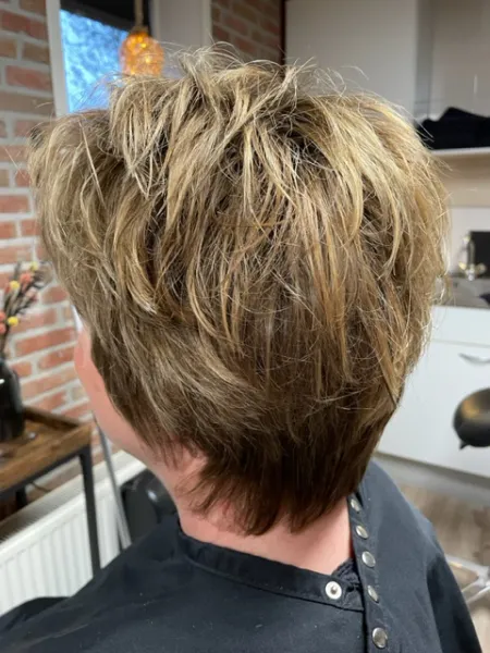 Deze dame heeft een kort opgeschoren kapsel waar de onderkant van het haar donker is geverfd en de bovenkant lichter. De overloop van licht naar donker heeft een natuurlijke overgang.